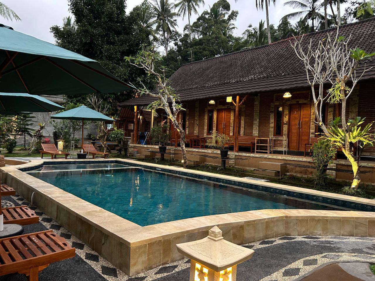 Lush green resort pool area surrounded by tropical trees and Balinese architecture